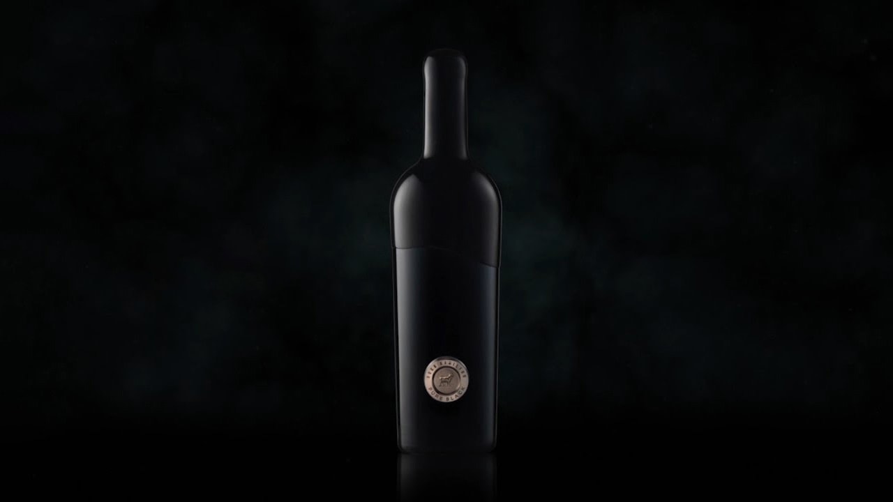 A photo of a black bottle of wine, posed in front of a black backdrop, the Hugh Hamilton 'Pure Black' circular label placed near the bottom of the bottle, 
