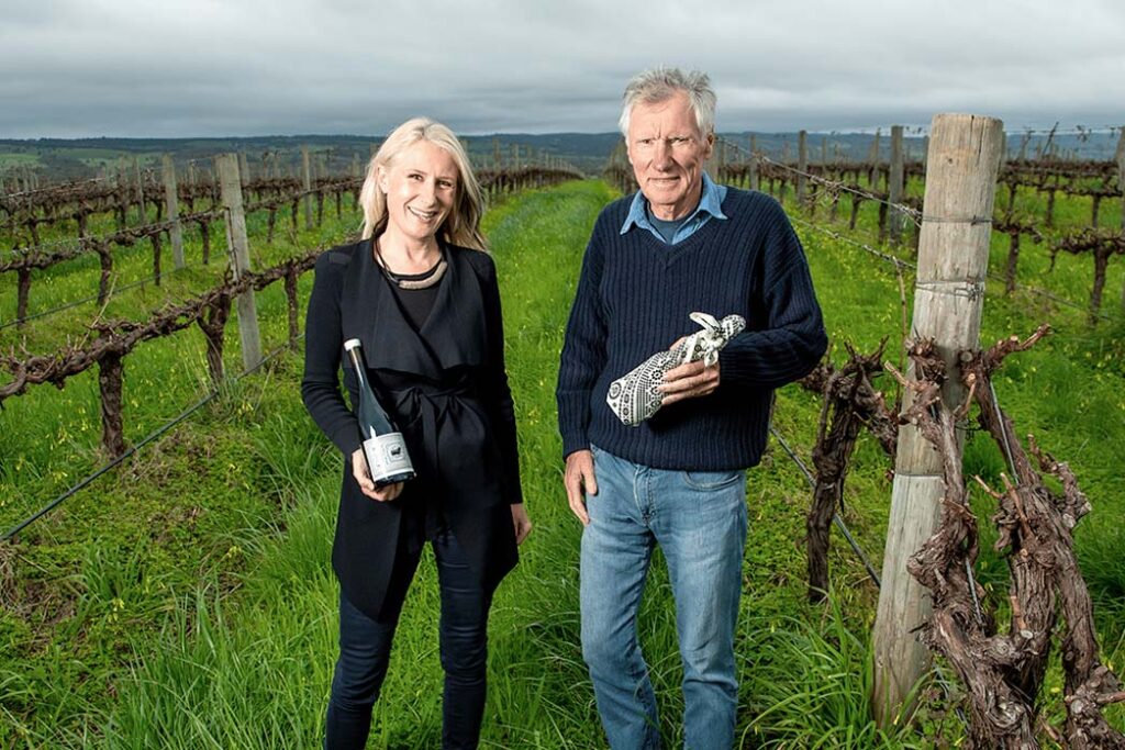 Mary and Hugh Hamilton, current leaders of Australia's Oldest Wine Family, in the vineyards with bottles of Wine.