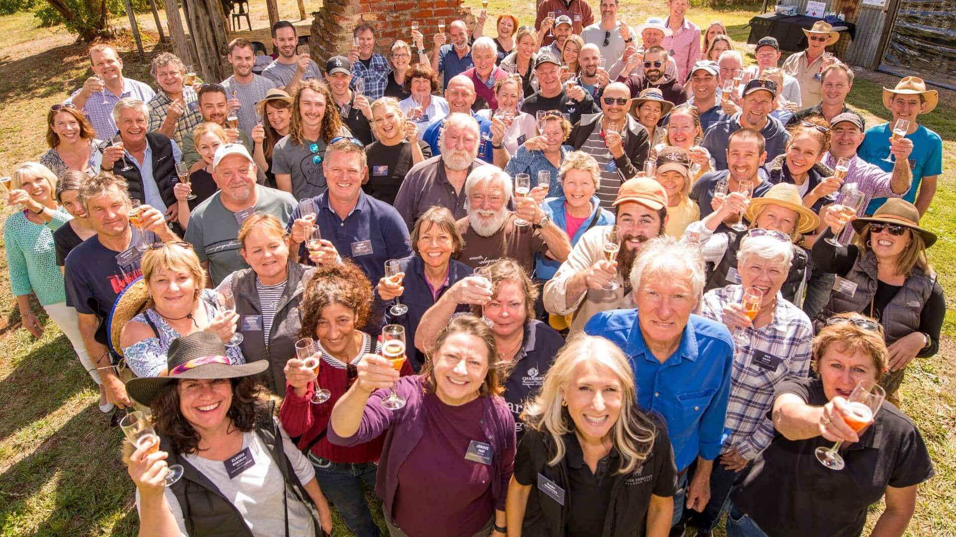 Hugh Hamilton Wines staff and club members standing in a group, smiling at the camera, and cheering their glasses of wine.
