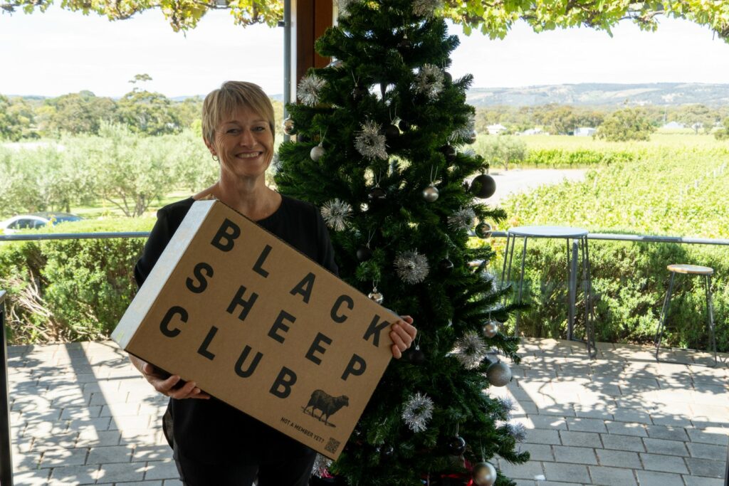 A Hugh Hamilton Wines customer holding a wine club shipment and smiling at the camera 