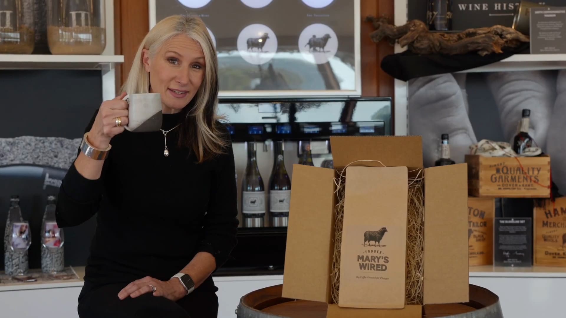 Mary Hamilton holding a pottery mug and sitting next to a package of Mary's Wired Coffee